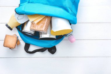 Beyaz ahşap arka planda farklı ürünleri olan okul çantası. Sırt çantası Gıda Programı