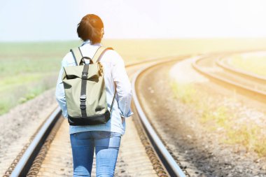Sırt çantalı bir gezgin tren yolu boyunca yürüyor.
