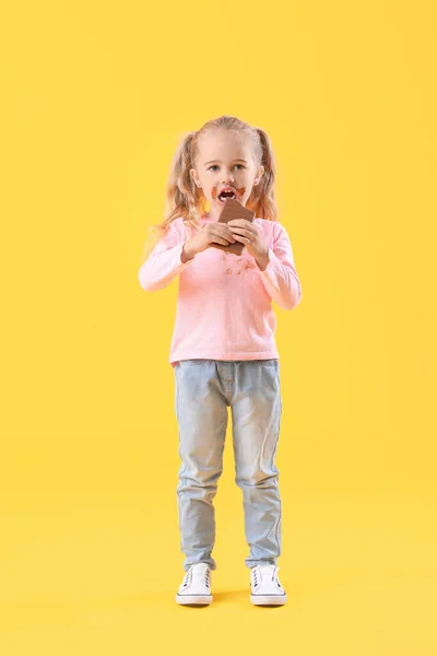 Маленькая Девочка Грязной Одежде Ест Шоколад Цветном Фоне — стоковое фото