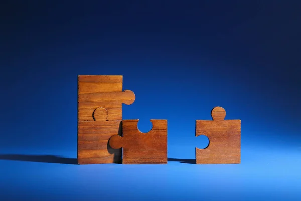 Wooden pieces of jigsaw puzzle on color background. Unity concept