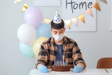 Üzgün Asyalı adam arkadaşsız doğum gününü kutluyor. Salgın kavramı