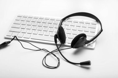 Beyaz arkaplanda kulaklığı olan PC klavyesi