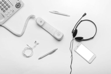 Kulaklık, kalem, kulaklık ve beyaz arka planda cep telefonu olan telefon.