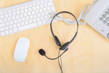 Kulaklık ve bilgisayar ve telefon, teknik destek ajanının masasında, üst görünüm