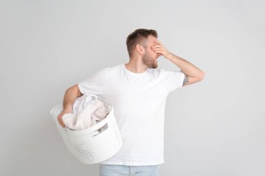 Gri arka planda kirli çamaşırları olan sorunlu bir adam.