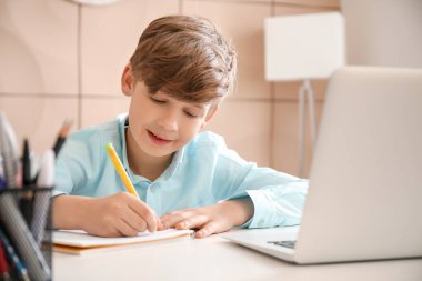 Evde ders çalışan sevimli küçük bir çocuk. Çevrimiçi eğitim kavramı