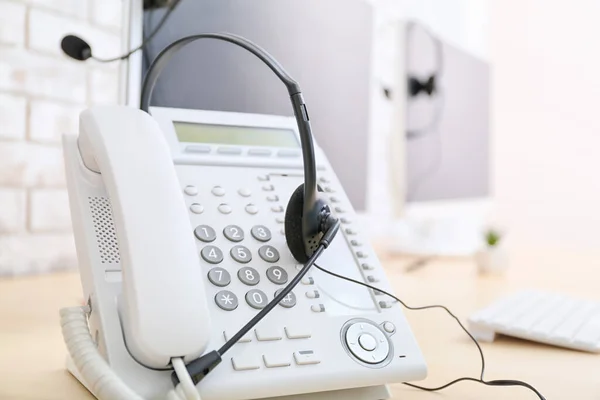 Headset and telephone on table of technical support agent in office