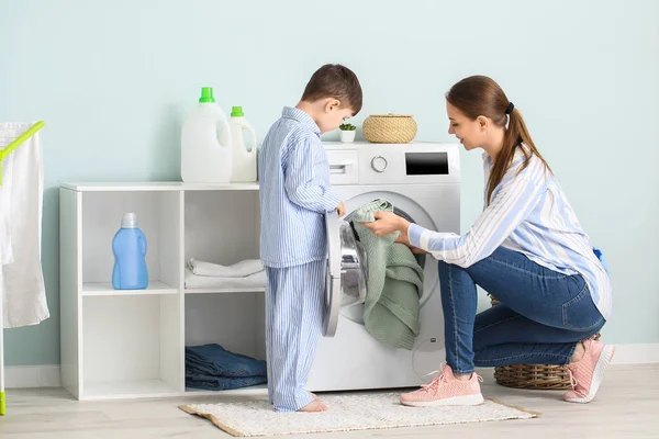 若いです女性とともに彼女の小さな息子行う洗濯に家で — ストック写真