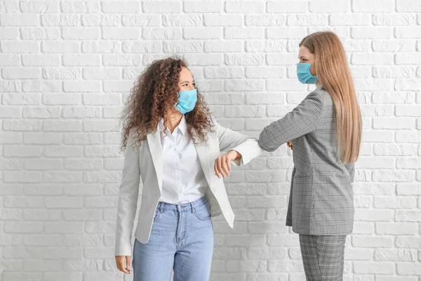 Mulheres Jovens Máscaras Protetoras Cumprimentando Uns Aos Outros Fundo Tijolo — Fotografia de Stock