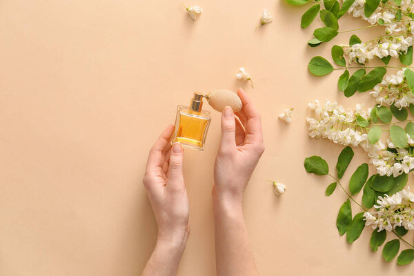 Женские руки с духами и цветами на цветном фоне
