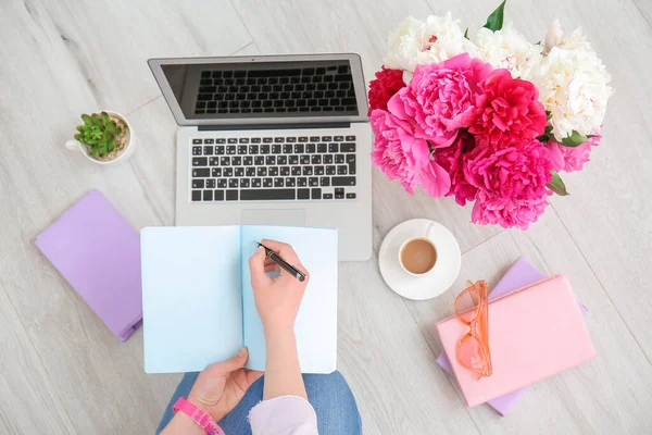 Vrouw Werkend Vloer Met Mooie Pioenroos Bloemen Laptop Bovenaanzicht — Stockfoto