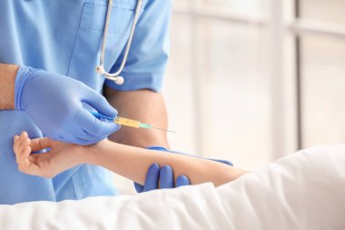 Hastane odasında hastayla çalışan kadın doktor, yakın plan.