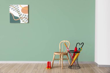 Şemsiyeler, sandalye ve çizmeler renkli duvarın yanında.
