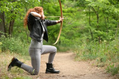 Dışarıda okçuluk yapan genç bir bayan.
