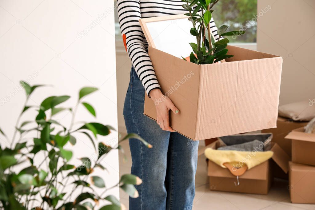Woman with belongings in cardboard box on moving day
