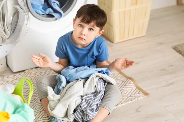 Evde kirli çamaşırları olan üzgün küçük bir çocuk.
