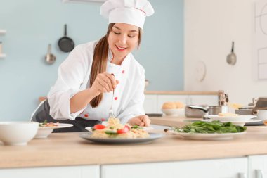 Kadın aşçı mutfakta lezzetli yemekler pişiriyor.