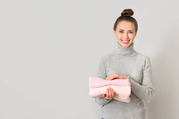 Молодая женщина с чистой прачечной на сером фоне
