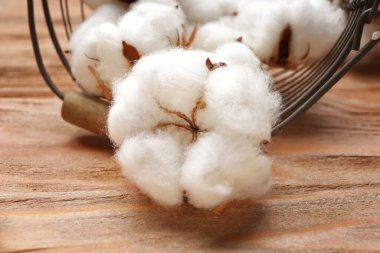 Tahta arka planda güzel pamuk çiçekleri olan sepet, yakın plan.