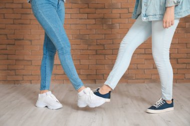 Tuğla duvarın yanında birbirlerini selamlayan genç kadınlar. Koronavirüs salgını sırasındaki sosyal mesafe kavramı