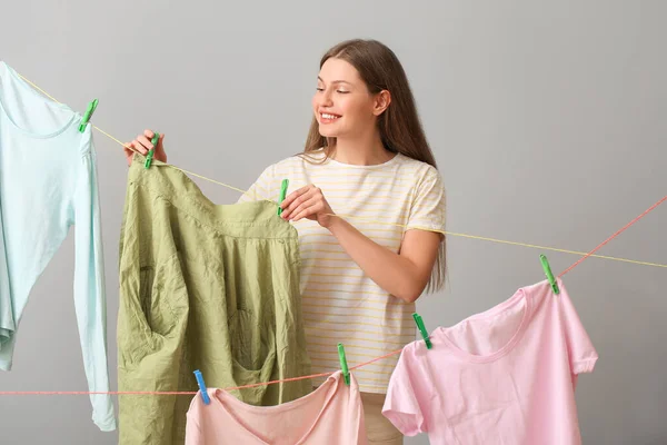 Jonge Vrouw Opknoping Schone Line Tegen Grijze Achtergrond — Stockfoto