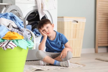 Evde kirli çamaşırları olan üzgün küçük bir çocuk.