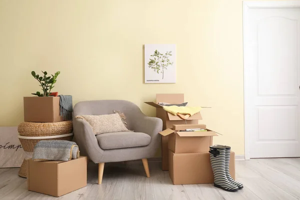 搬迁日新公寓内装有个人物品和扶手椅的纸板箱 — 图库照片