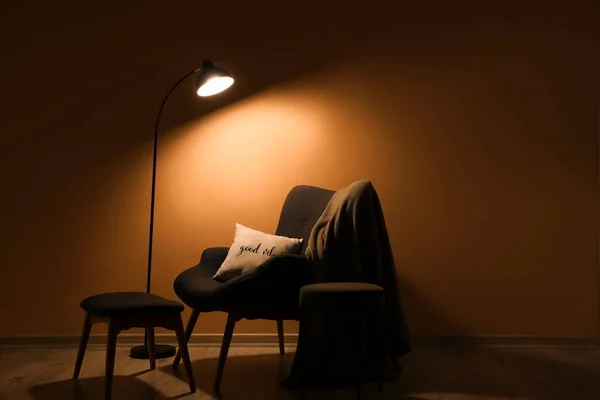 暗い部屋で光るランプと居心地の良いアームチェア — ストック写真