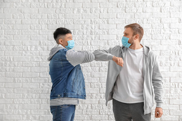 Young men greeting each other on white background. Concept of epidemic