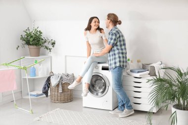 Mutlu genç çift evde çamaşır yıkıyor.