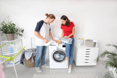 Mutlu genç çift evde çamaşır yıkıyor.