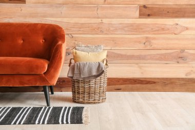 Yatak odasındaki kanepenin yanında yastık ve ekoseli sepet.