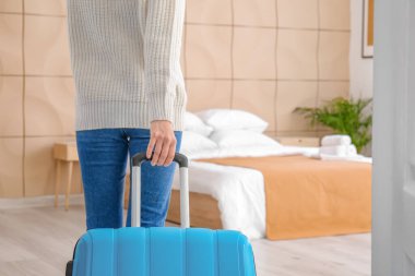 Bavullu genç bir kadın otel odasında uyuyor.