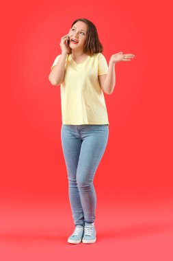 Renkli arka planda cep telefonuyla konuşan güzel genç kadın.