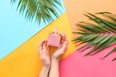 Renkli parfümlü ve tropikal yapraklı kadın elleri