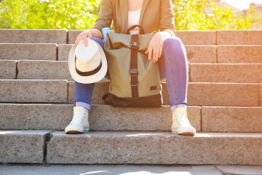 Sırt çantalı kadın gezgin parkta merdivenlerde oturuyor.