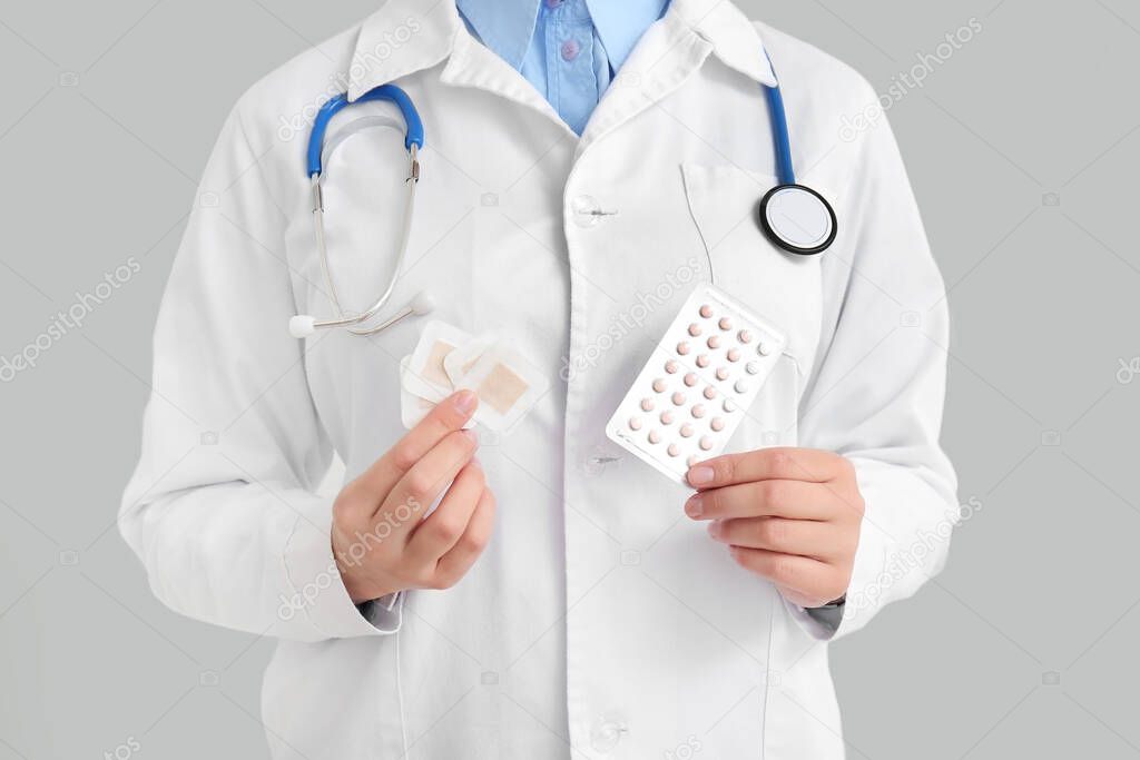 Female gynecologist with different contraceptives on white background, closeup