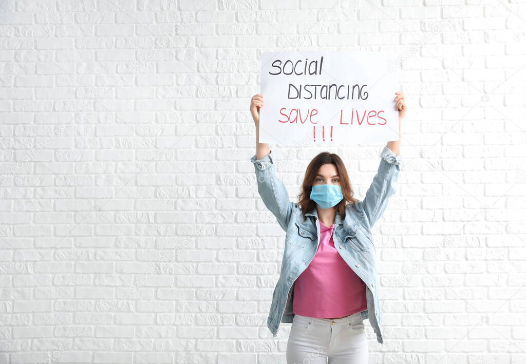 Young woman holding paper with text SOCIAL DISTANCE. SAVE LIVES on white background. Concept of epidemic