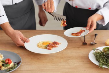 Erkek ve kadın aşçılar mutfakta yemek pişiriyor.