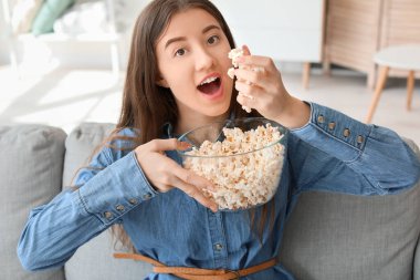 Patlamış mısırlı güzel bir kadın evde film izliyor.