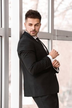 Pencerenin yanındaki şık takım elbiseli yakışıklı genç adam.
