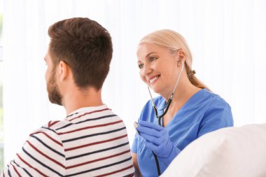 Hastane odasında hastayla çalışan olgun bir kadın doktor.