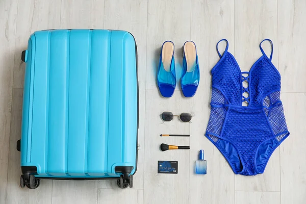 Packed suitcase and accessories on wooden background