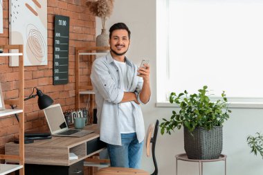 Evde cep telefonu olan yakışıklı bir genç.