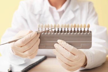 Diş rengi örnekleri ve aleti olan kadın dişçi, yakın plan.