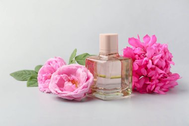 Gri arka planda bir şişe çiçek parfümü.