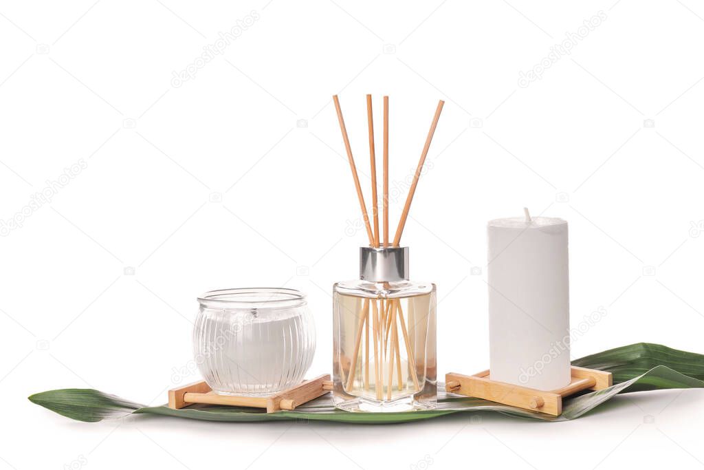 Reed diffuser and candles on white background