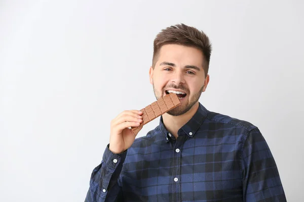 Hafif Arka Planda Lezzetli Çikolataları Olan Yakışıklı Genç Adam — Stok fotoğraf