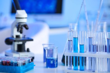 Laboratuvardaki masada mikroskop ve cam eşyalar.