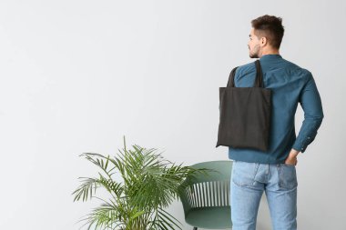 Çevre çantalı genç adam ışık duvarına yaslandı.